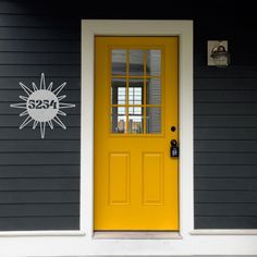 a yellow door on a gray house with the number 205 painted on it's side