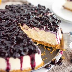 a cheesecake with blueberries on top is cut into slices and sits on a plate