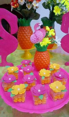 there are many cupcakes on the table with flowers in vases next to them