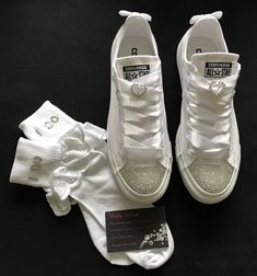 a pair of white sneakers and socks on a black surface with a card next to them