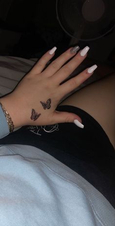 a woman's hand with butterfly tattoos on it