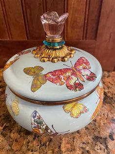 a ceramic box with butterflies on it sitting on a counter top next to a wooden door