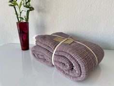 two folded towels sitting on top of a table next to a vase