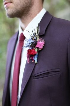 a man in a suit and tie wearing a flower boutonniere on his lapel