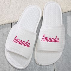 white slippers with the word amanda written in red on them sitting on a wooden floor