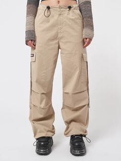 Arm yourself with ’90s and noughties attitude! Take a look at our cargo parachute pants in beige, featuring a baggy fit, utility pockets and adjustable toggle waist and hems. Find y2k pants, retro trousers & more aesthetic clothes at Minga London. Tech Cargo Pants, Jeans With Chains, Retro Trousers, Parachute Cargo Pants, 90s Pants, Denim Button Skirt, Minga London, Parachute Cargo, Y2k Pants