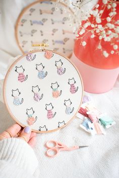 a person is holding a small embroidery kit in front of a vase with baby's breath flowers