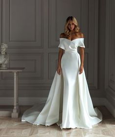 a woman in a white wedding dress standing next to a table with a vase on it