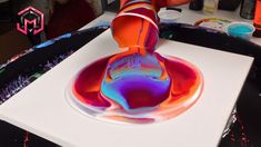 a person is painting with colorful liquid on a white surface and it looks like they are doing something