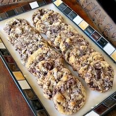 chocolate chip cookies sitting on top of a white plate next to a glass tile counter