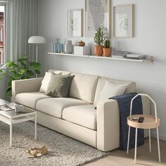 a living room filled with furniture next to a window and a plant on the wall