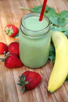 a smoothie in a mason jar with strawberries and bananas on the table next to it