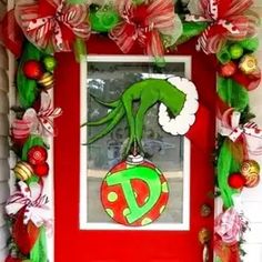 a red door decorated with christmas decorations and an ornament hanging from it's side