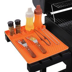 an orange tray with utensils and bottles on it next to a bbq