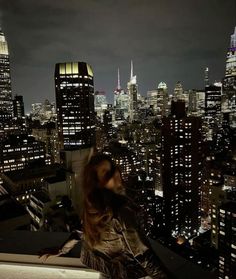 a woman standing on top of a tall building in front of a cityscape