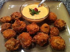 some fried food is on a plate with a bowl of dipping sauce in the middle