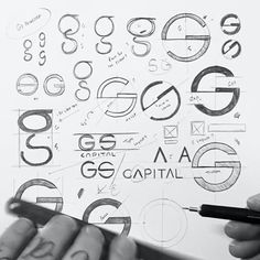 two hands are holding a pen and drawing on paper with various symbols in the background