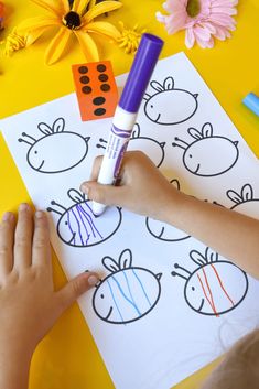 a child's hands drawing on paper with crayons and flowers in the background