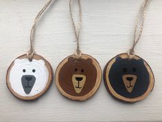 three wooden ornaments with bears on them are hanging from string and decorated with twine