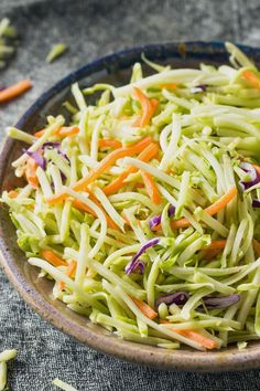 shredded carrots and cabbage in a bowl on a tablecloth with other food items