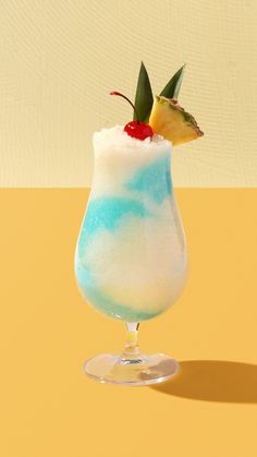 a blue and white drink in a glass with a pineapple garnish on top