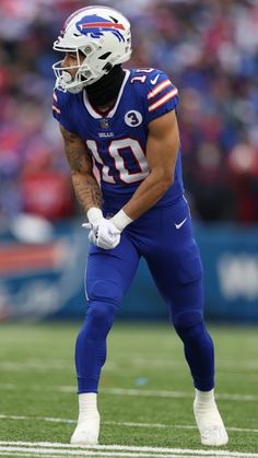 a football player standing on the field with his hands in his pockets and wearing a helmet