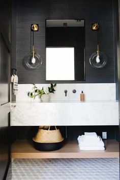 a bathroom with black walls and white counter tops, gold fixtures and a mirror above the sink