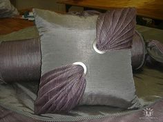 two decorative pillows on top of a bed covered in purple fabric and twine ribbons