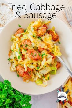 a white bowl filled with pasta and sausage on top of a table next to some parsley