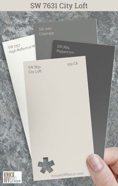 someone holding up some white and gray paint samples with the words sw 761 city loft on them