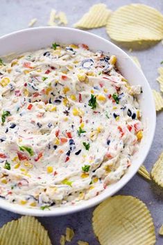 a bowl filled with white dip surrounded by chips