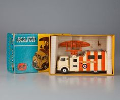 an orange and white toy truck in a box with the lid open to show it's contents