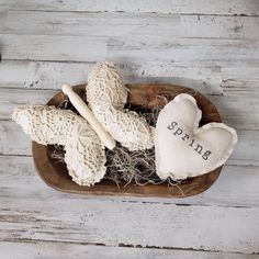 an arrangement of knitted items in a bowl on a white wooden background with the word spring written on it