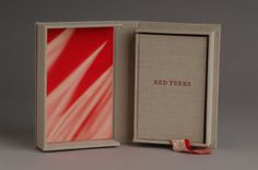 an open book with red trees on the cover and ribbon tied around the inside box