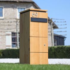 a wooden mailbox sitting on top of a lush green field next to a house