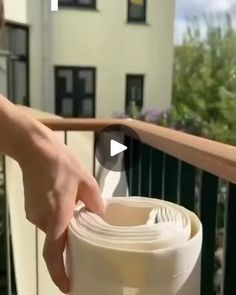 a person holding a roll of white paper on top of a balcony