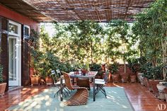 an outdoor dining area with potted plants and wicker furniture on the patio floor