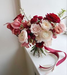 a bouquet of flowers sitting on top of a white counter next to a window sill