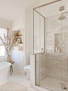 a bathroom with a tub, toilet and shower in it's corner area next to a window