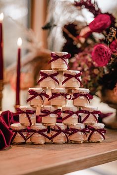 a stack of cookies sitting on top of a wooden table next to candles and flowers