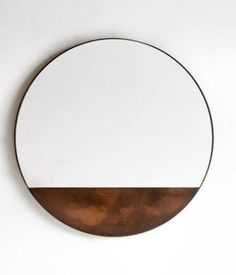 a round mirror hanging on the wall above a white counter top with a brown edge