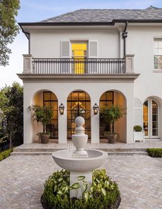 a large white house with a fountain in the front yard