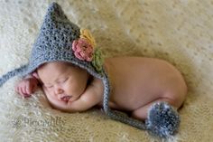 a newborn baby wearing a crocheted hat with flowers