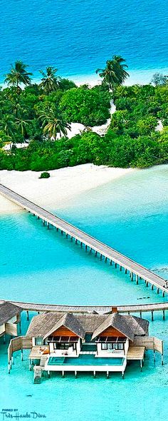 an aerial view of the water and beach in front of a pier with thatched huts