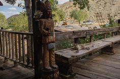 a wooden bench sitting on top of a wooden deck next to a statue with a cat