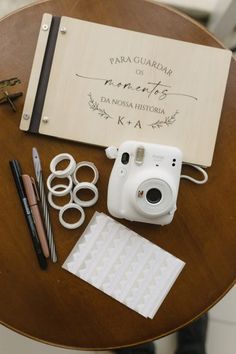 a wooden table topped with a white camera next to some scissors and other items on top of it