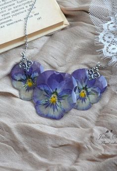 three purple flowers are hanging from a necklace