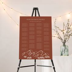 an easel stands next to a table with a mountain wedding seating plan on it