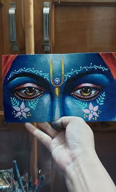 a hand holding up a card with an image of a woman's face painted on it