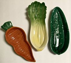 three ceramic vegetables are lined up on a table